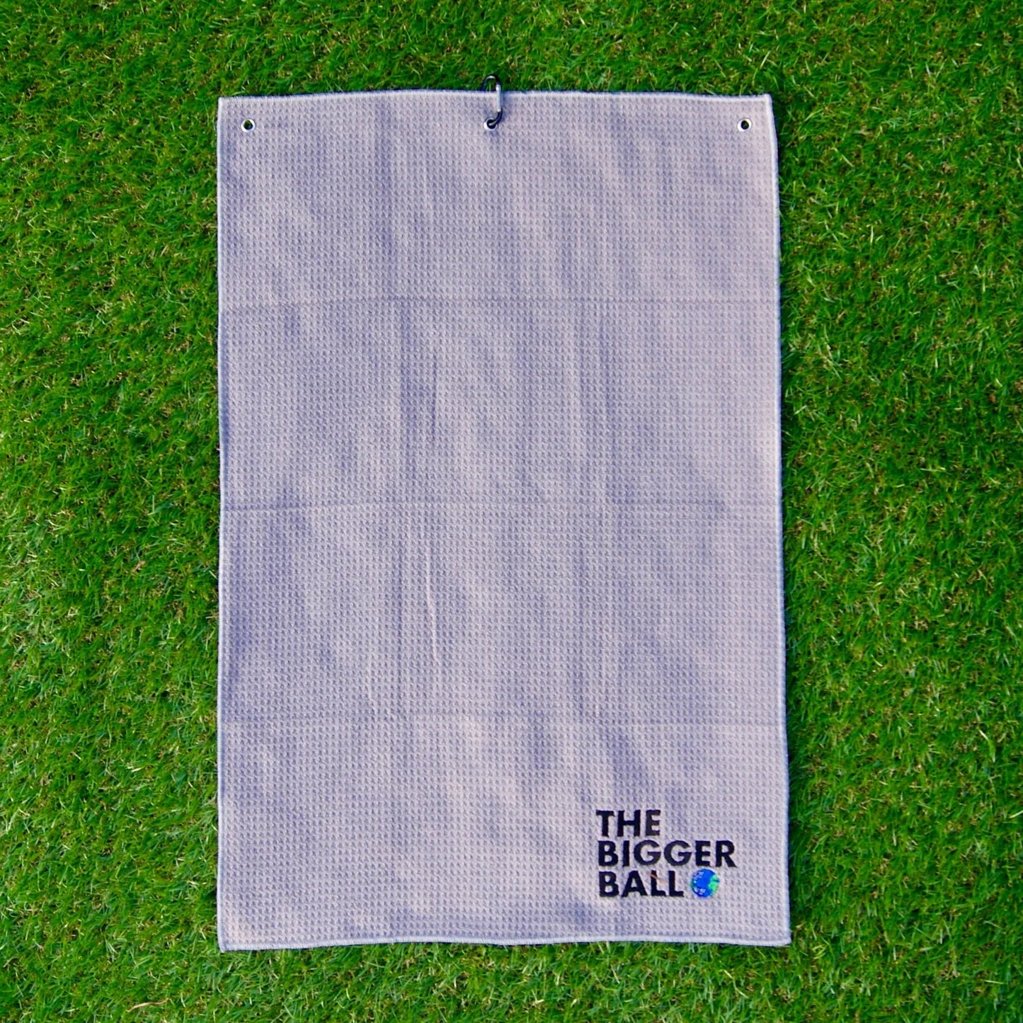 Bamboo Microfibre Golf Towel with Carabiner Clip on Grass - Eco-Friendly Golfer's Club Cleaner